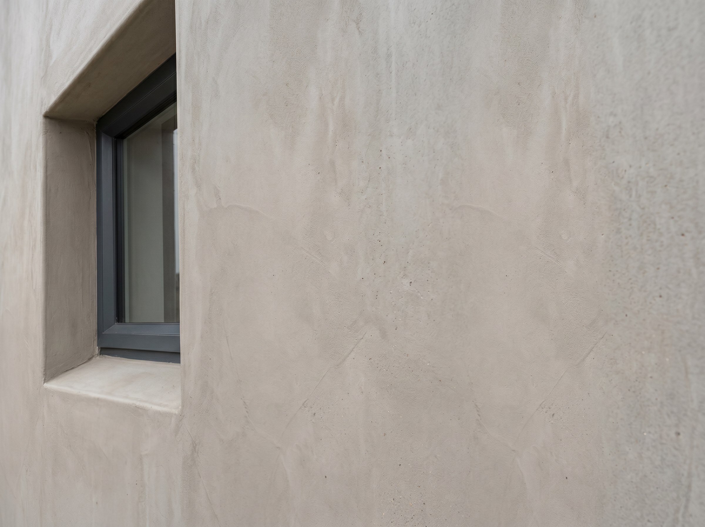 Close-up of a completed exterior cementitious wall finish at a window reveal