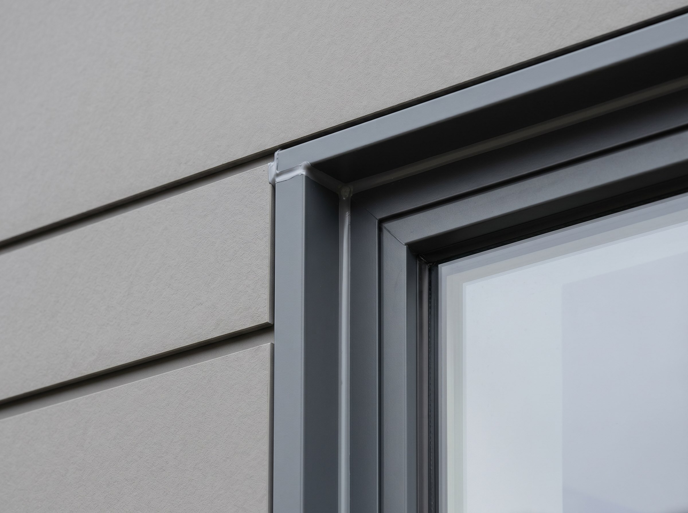 Finished cladding junction at a window reveal with aluminium trim
