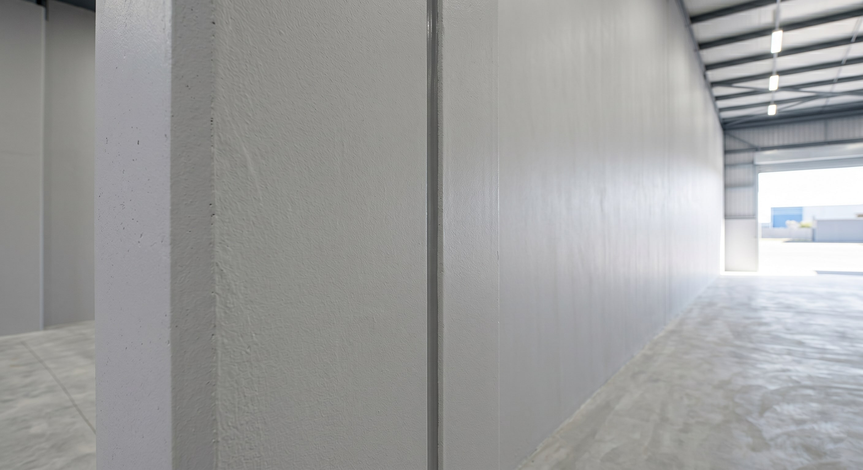 Close-up of completed wall and column base coating in a commercial warehouse interior