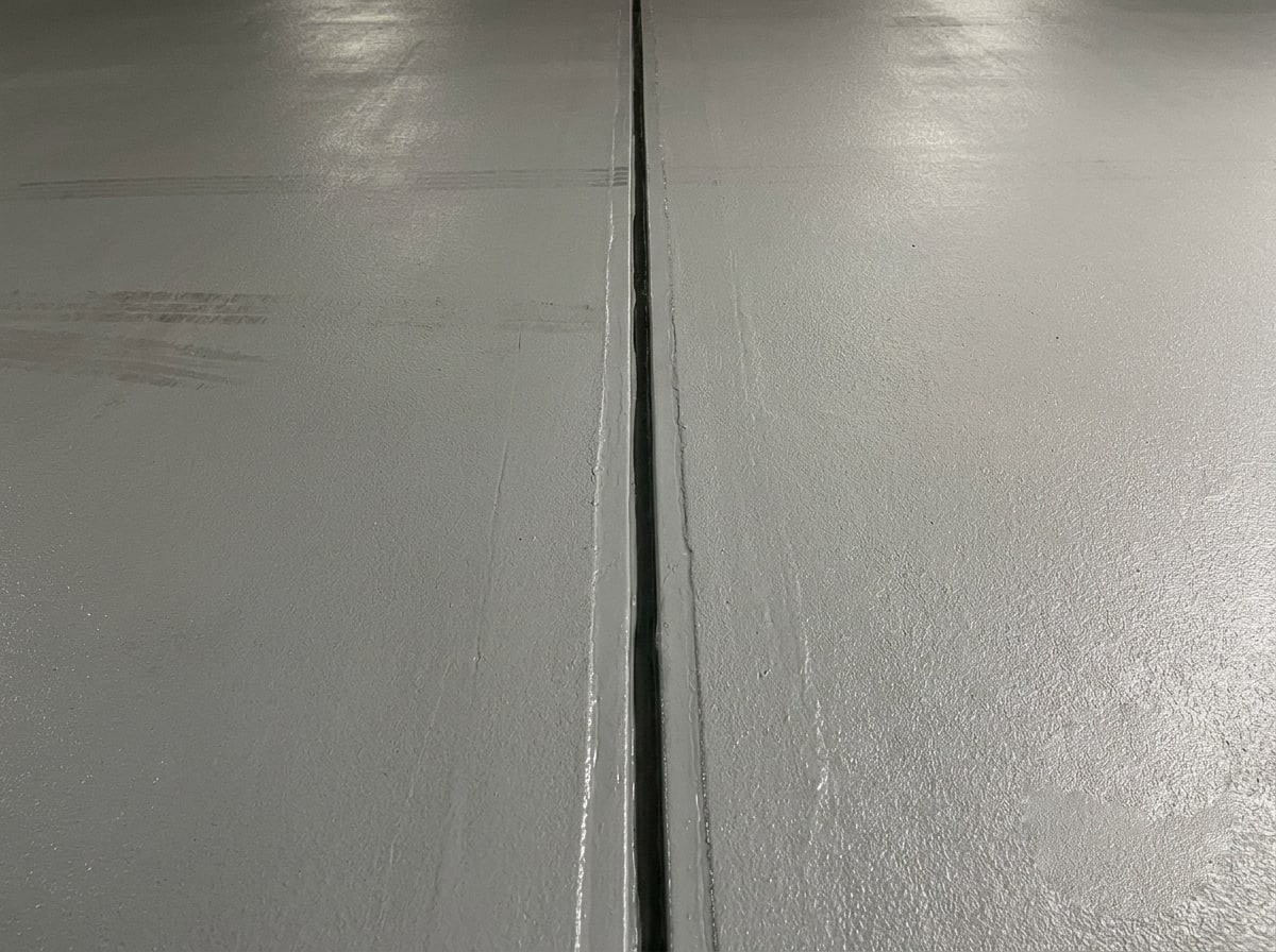 Close-up of a completed expansion joint and deck coating line in a parking structure