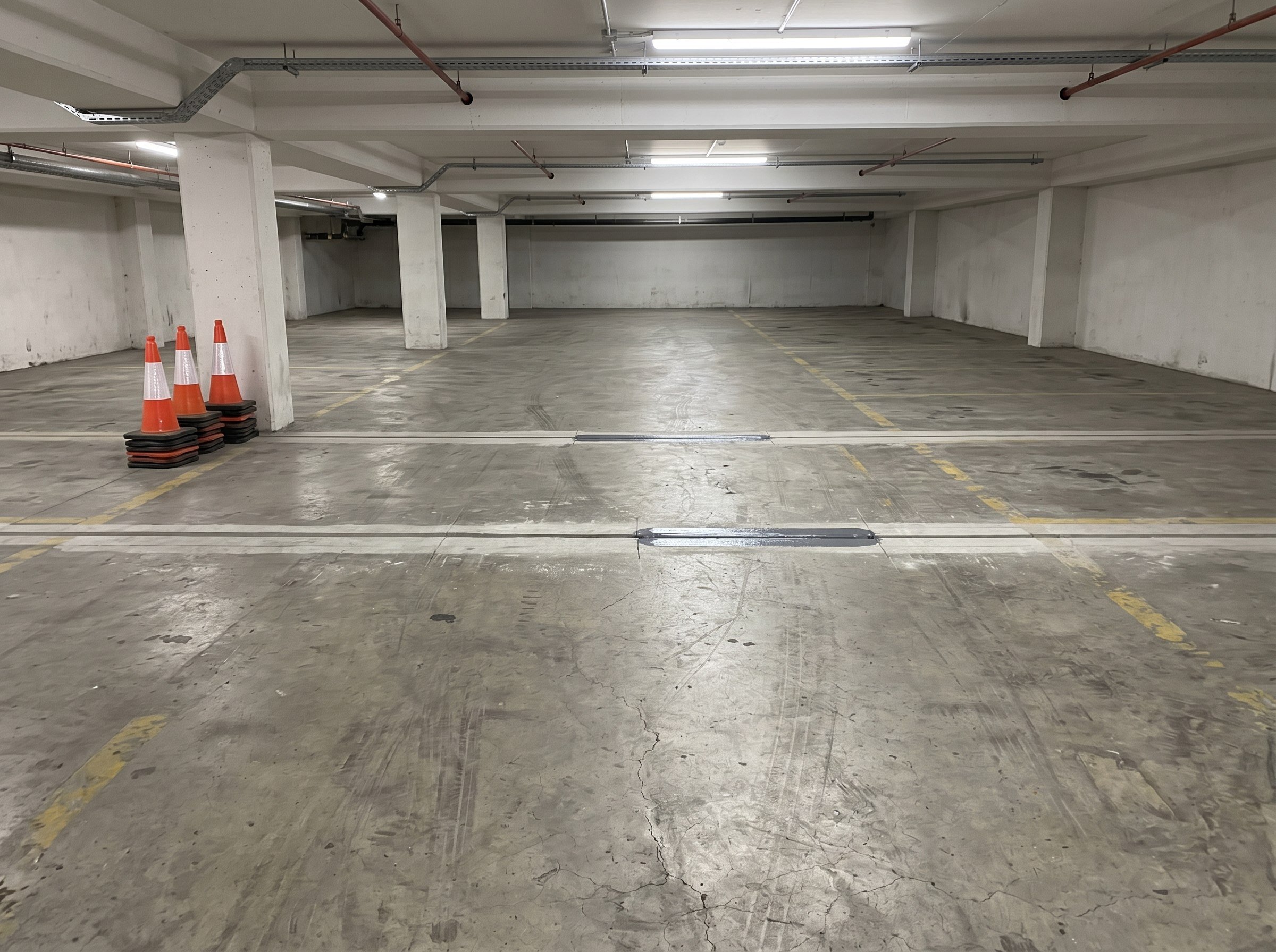 Wide view of renewed expansion joints across one lane of a small basement parking area